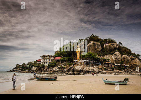 A woman looking at the sea on Khao Takiab beach in Hua Hin. In front is the temple at the end of the beach. This is the quiet part of Hua Hin. Stock Photo