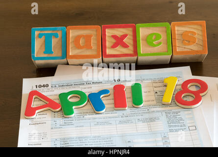 Wooden letters on top of 1040 income tax form for 2016 showing tax day for filing is April 18 2017 Stock Photo