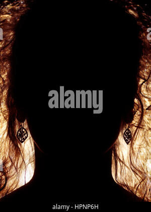 Abstract woman face dark silhouette with long hair lit from behind Stock Photo