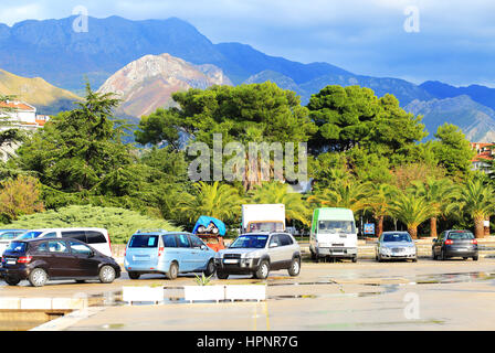 Car parking in front of green trees and mountains Stock Photo
