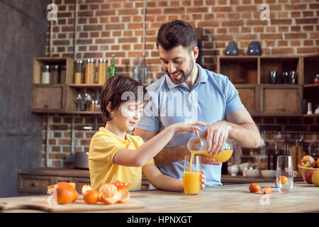 father and son pouring fresh juice in glass Stock Photo