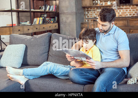 father and son reading newspaper together at home Stock Photo