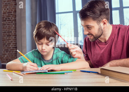 father helping concentrated son doing homework Stock Photo