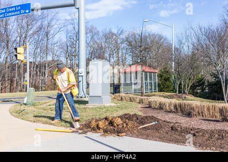 Fairfax, USA - February 18, 2017: Worker digging soil in ground for landscaping Stock Photo