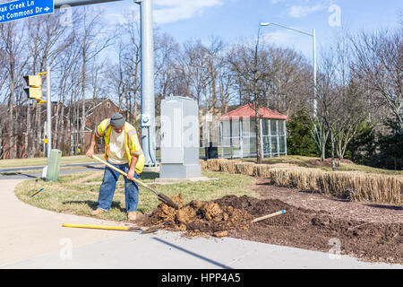 Fairfax, USA - February 18, 2017: Worker digging soil in ground for landscaping Stock Photo