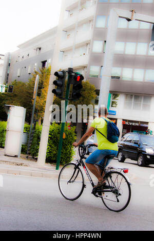 Man riding his bike crosses the street while the traffic light is red and he should wait it to become green: breaking the traffic rules Stock Photo