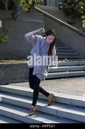 woman with long dark hair walking down stairs Stock Photo