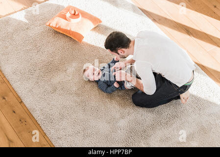 Father changing diapers and playing with his baby son Stock Photo