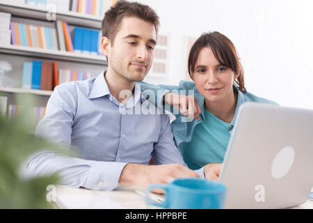 Young couple at home using a computer and connecting to internet, communication and technology concept Stock Photo
