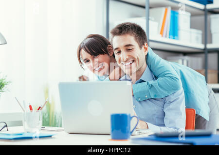 Happy young couple at home using a laptop and surfing the web, they are having fun and relaxing, togetherness and leisure concept Stock Photo