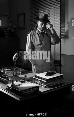 Attractive detective standing next to his desk, 1950s style office. Stock Photo