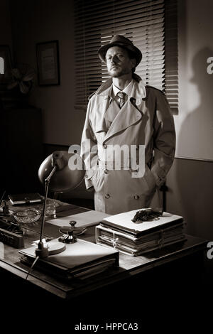 Attractive detective standing next to his desk, 1950s style office. Stock Photo