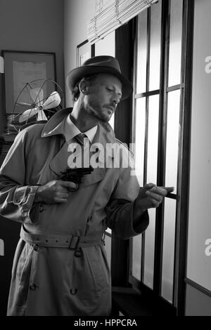 Attractive spy agent peeking from an office window, film noir. Stock Photo