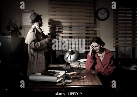 Confident detective standing in his office interviewing a young sad woman. Stock Photo