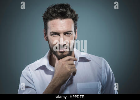 Handsome smiling man with hand on chin posing Stock Photo