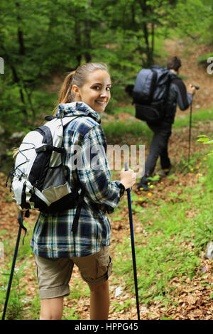 Young couple enjoying nordic walking in a forest, woman looking at camera Stock Photo