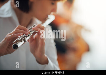 Professional female flute player performing with classical music symphony orchestra, unrecognizable person Stock Photo