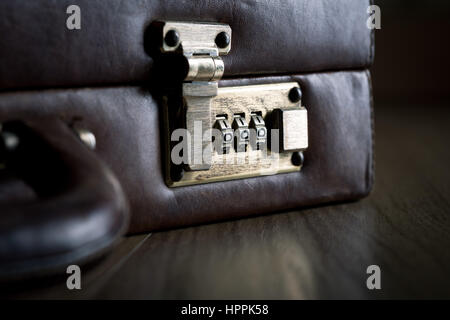 Leather briefcase lock and handle close-up on dark hardwood floor. Stock Photo
