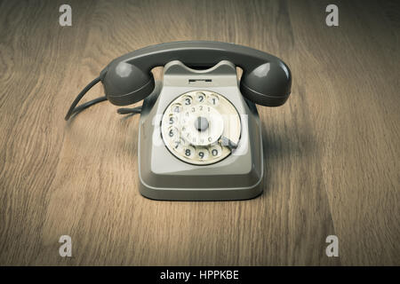 Vintage gray telephone on hardwood surface desk or floor. Stock Photo