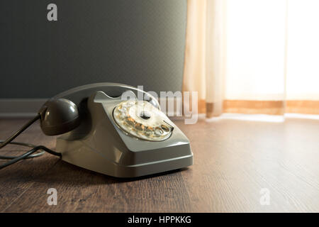 Gray vintage table on hardwood floor next to a window. Stock Photo