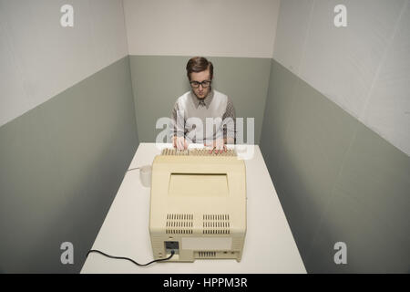 Vintage nerd guy working on old computer in a small room. Stock Photo