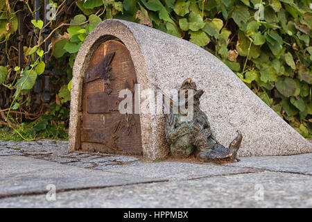 A dwarf, symbol of Wroclaw in Poland guards the entrance of a small building, sleeping next to the door Stock Photo