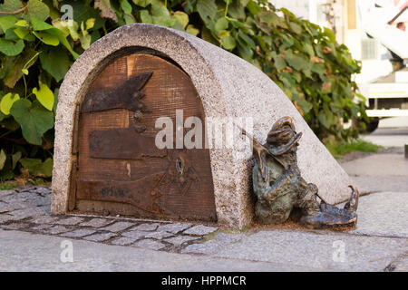A dwarf, symbol of Wroclaw in Poland guards the entrance of a small building, sleeping next to the door Stock Photo