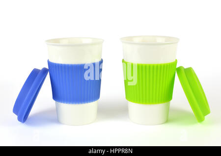 Two white containers for coffee or hot drinks with blue and green thermo sleeves and lids beside them, isolated on white Stock Photo