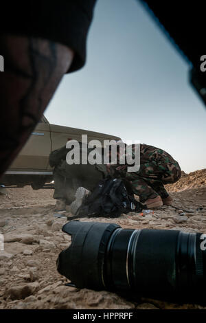 Harry Martinez and two yazidi fighters take cover behind a pickup truck after coming under bombardment from Islamit State Mortars Stock Photo