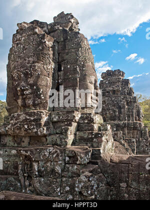 A close up view of some of the many smiling stone faces of Prasat Bayon - the last state temple to be built at the Angkor complex on a sunny day. Stock Photo