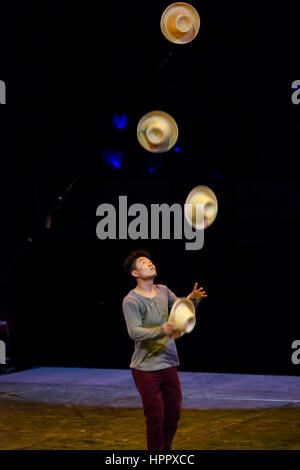 Asian man Juggling hats. A muse Circus. Compañía Les 7 doigts de la main Stock Photo