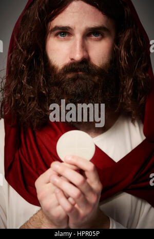 Jesus Christ holding holy Eucharist in hands Stock Photo