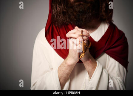 Jesus with folded hands and rosary Stock Photo
