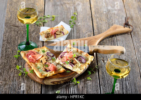 Tarte Flambee from Alsace with sour cream, onions, mushrooms and serrano ham, served with local Alsatian wine Stock Photo