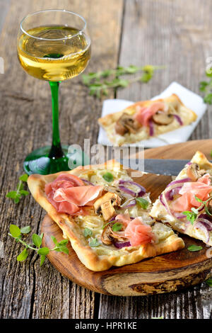 Tarte Flambee from Alsace with sour cream, onions, mushrooms and serrano ham, served with local Alsatian wine Stock Photo