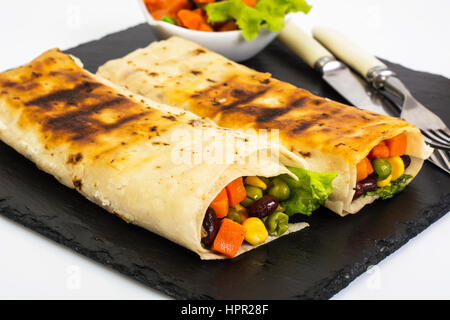Roll from lavash with vegetables on black stone. Studio Photo Stock Photo