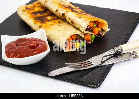 Roll from lavash with vegetables on black stone. Studio Photo Stock Photo