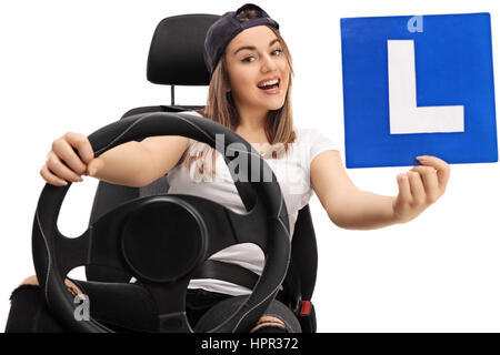 Joyful young girl showing an L-sign and sitting in a car seat isolated on white background Stock Photo