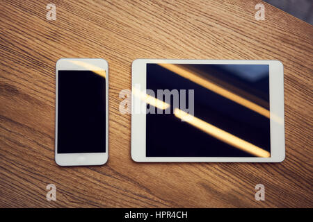 Smartphone and tablet on wooden desk - mockup Stock Photo