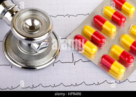 Electrocardiogram graph report with stethoscope and pills on it Stock Photo