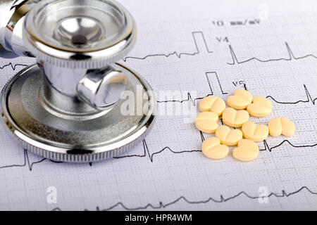 Electrocardiogram graph report with stethoscope and pills on it Stock Photo
