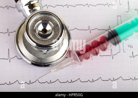 Electrocardiogram graph report with stethoscope and pills on it Stock Photo