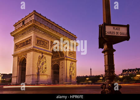 Dawn at the Arc de Triomphe in Paris, France. A sign on a lamppost reads Place Charles de Gaulle and the Eiffel Tower is visible in the distance. Stock Photo