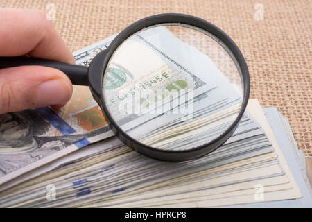 Magnifying glass is held over the banknote bundle of US dollar Stock Photo