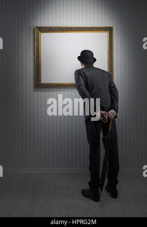 Retro elegant man standing and observing a empty frame in a museum Stock Photo