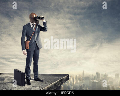 Businessman with gas mask looking through binoculars with a polluted city as background Stock Photo