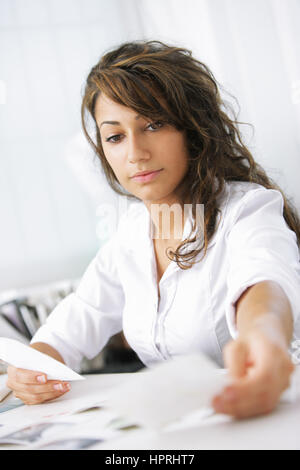 Female photographer examines the photographs, is sitting at her desk in the office Stock Photo