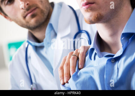 Doctor comforting a young patient after telling him bad news. Stock Photo