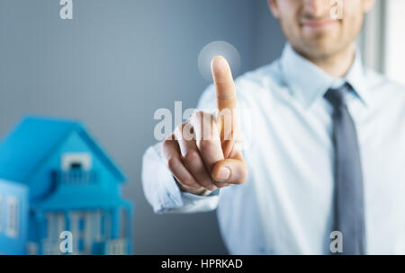 Man using touch screen interface with model house on background. Stock Photo
