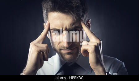 Exhausted young businessman with headache touching his head. Stock Photo